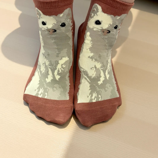 おこじょ（オコジョ）柄ソックスの着用イメージ、木の床に立つ足元｜おこじょ屋